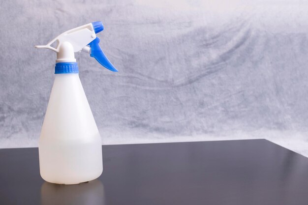 Bouteille blanche pour arroser les plantes sur table