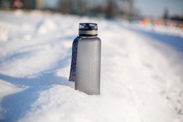 Bouteille de boisson en plastique gris spotive dans la neige.