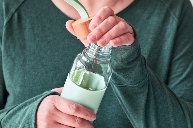 Bouteille de boisson réutilisable entre les mains des femmes. Concept zéro déchet pour sauver notre planète. Concept de mode de vie de consommation consciente.