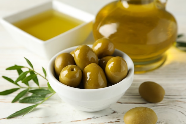 Bouteille et bol d'huile d'olive, bol d'olives sur bois, gros plan