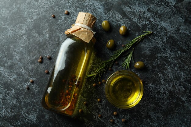 Bouteille et bol avec de l'huile d'olive et des épices sur noir fumé