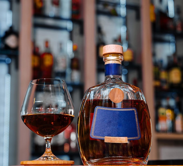 Photo bouteille de brandy élégante et verre sur le comptoir du bar