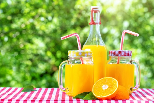 Bouteille et canettes de maçon avec jus d'orange sur vert naturel