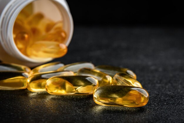 Bouteille avec capsules Omega-3 sur fond noir.