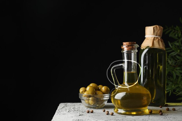 Bouteille et carafe d'huile d'olive contre le noir, espace pour le texte