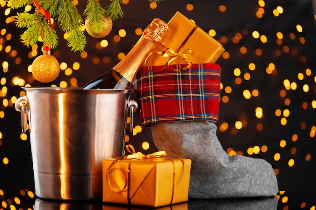 Bouteille de champagne et bas de Noël avec des cadeaux contre guirlande