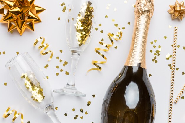 Photo bouteille de champagne avec des confettis de paillettes colorées et un espace de boîte-cadeau pour le texte sur fond coloré vue de dessus célébration hilarante de noël et d'anniversaire