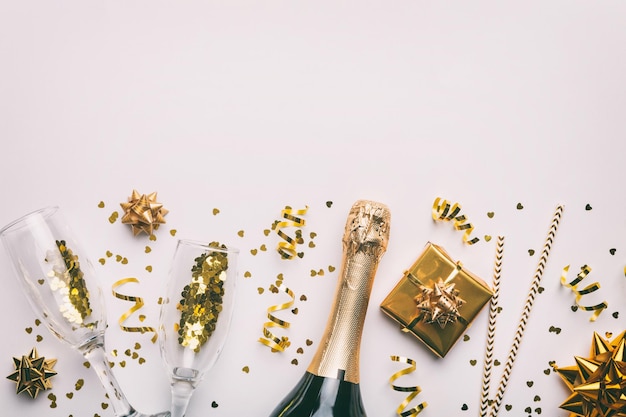 Bouteille de champagne avec des confettis de paillettes colorées et un espace de boîte-cadeau pour le texte sur la vue de dessus de fond coloré Hilarante fête de Noël et d'anniversaire