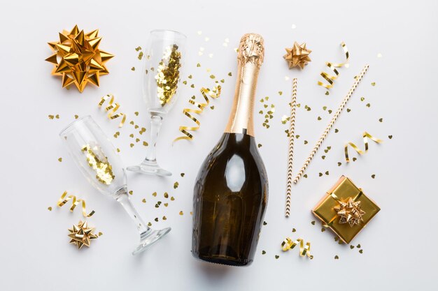 Bouteille de champagne avec des confettis de paillettes colorées et un espace de boîte-cadeau pour le texte sur la vue de dessus de fond coloré Hilarante fête de Noël et d'anniversaire