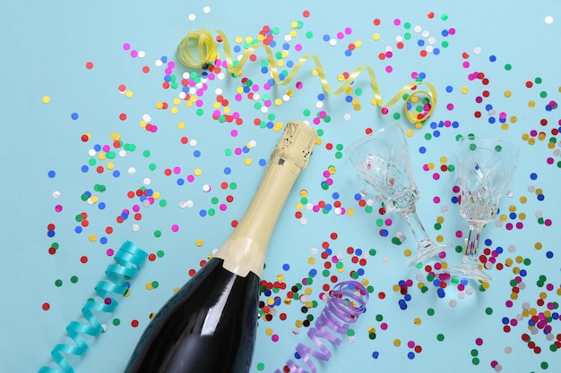 Bouteille de champagne et confettis avec streamer sur fond bleu