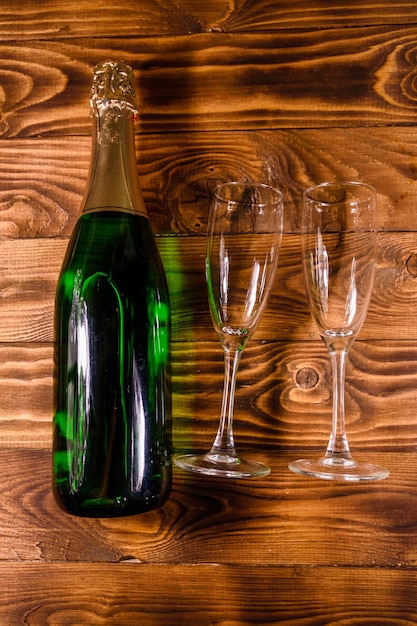 Bouteille de champagne et deux verres à vin sur une table en bois rustique. Vue de dessus