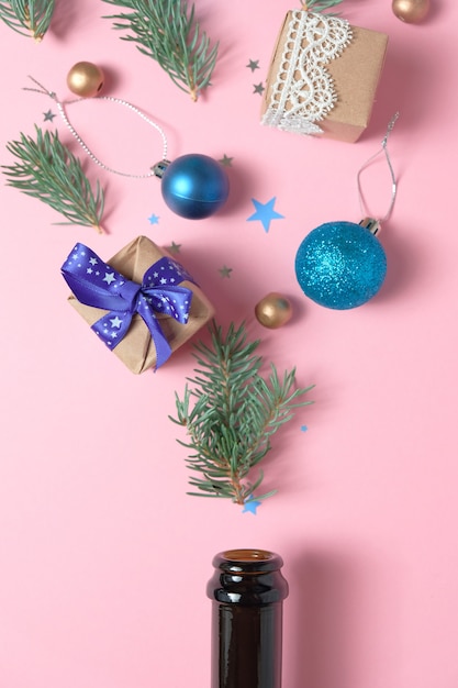 Bouteille de Champagne avec différentes décorations de Noël sur rose