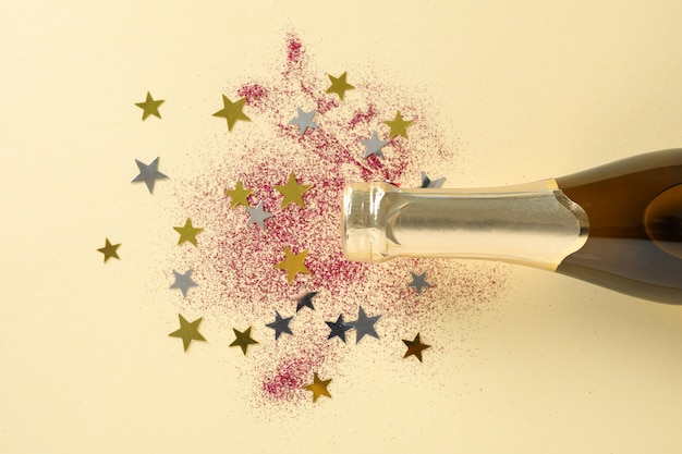 Bouteille de champagne et paillettes sur beige, espace pour le texte