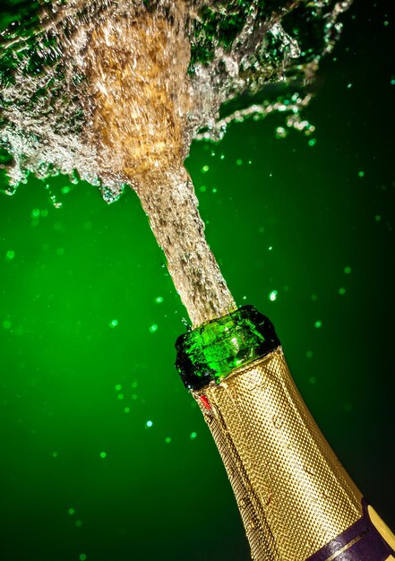 Bouteille de champagne avec splash sur fond vert