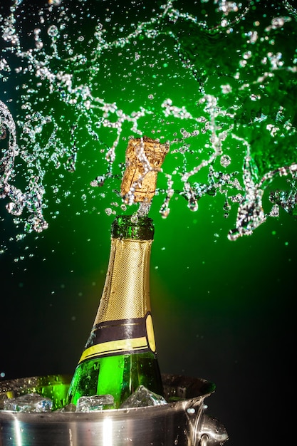 Photo bouteille de champagne avec splash sur fond vert