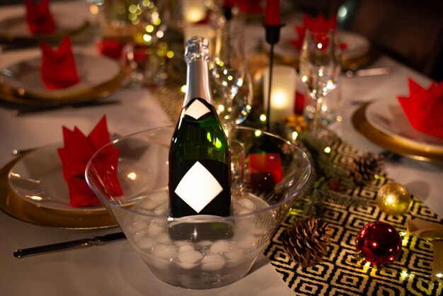 Bouteille de champagne sur une table de fête de fête de Noël avec verre de vin sur une décoration brillante rouge et or