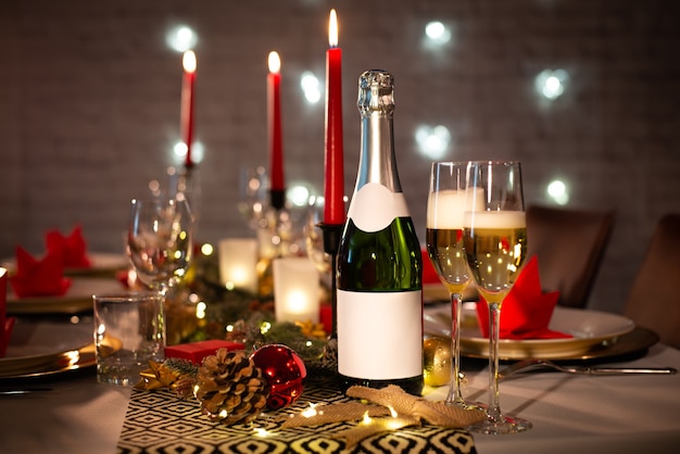 Bouteille de champagne sur une table de fête de fête de Noël avec verre de vin sur une décoration brillante rouge et or