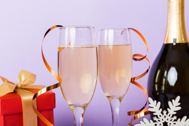 Bouteille de champagne avec verres à confettis et décor de noël sur fond de vacances coloré Décorations de nouvel an à plat