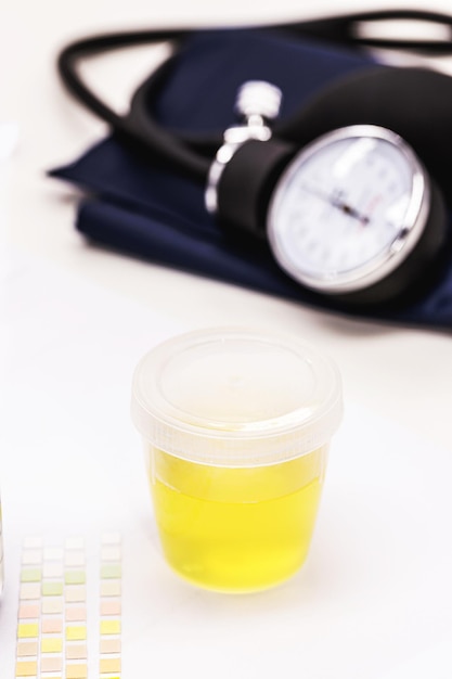 Photo bouteille ou collecteur d'urine avec sphygmomanomètre sur le côté concept de test d'urine d'hypertension examen médical