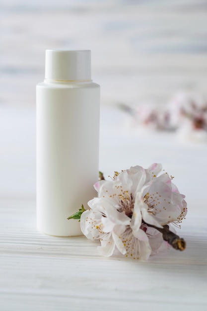 Photo bouteille de cosmétiques de soin du corps blanc avec des fleurs se bouchent