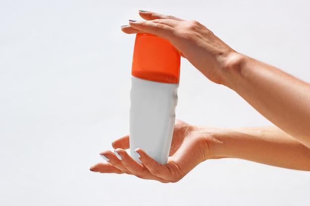 Bouteille de crème solaire dans les mains des femmes