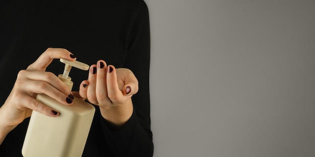 Bouteille de désinfectant pour les mains ou de savon dans les mains des femmes