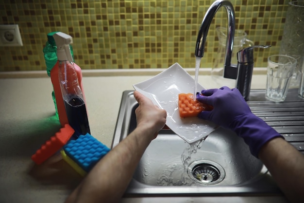 Une bouteille avec un détergent à vaisselle respectueux de l'environnement sur le fond d'une femme au foyer qui lave la vaisselle