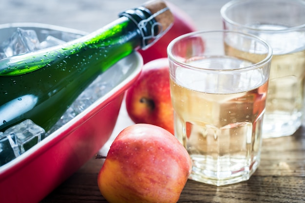 Bouteille et deux verres de cidre sur la table en bois