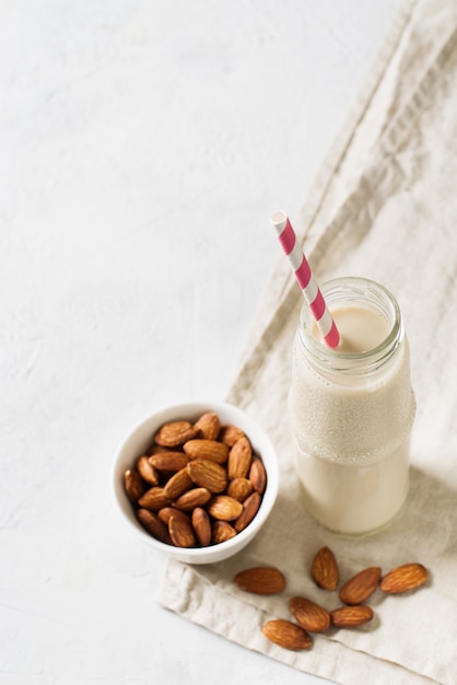 Bouteille avec du lait d'amandes et quelques amandes sur blanc