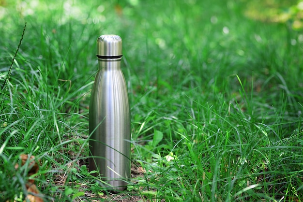 Bouteille d'eau Bouteille d'eau thermo réutilisable en acier sur l'herbe verte