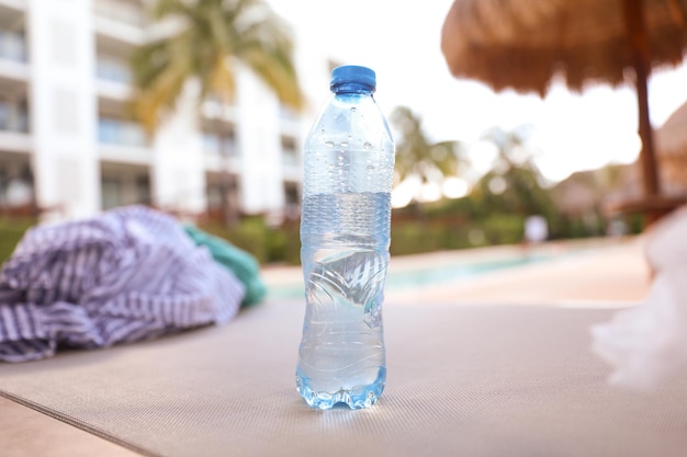 Une bouteille d'eau est à l'envers sur une chaise devant une piscine.