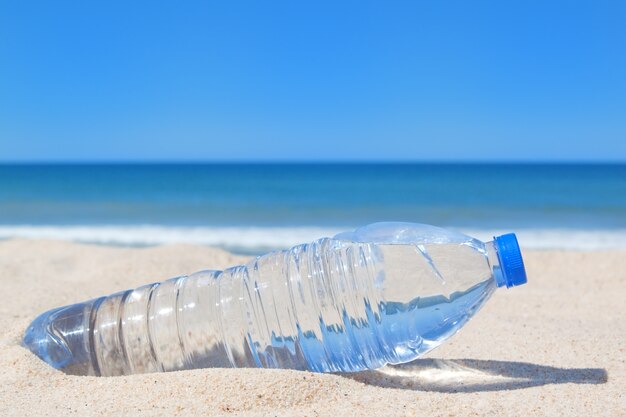 Une bouteille d'eau fraîche sur la plage près de la mer.