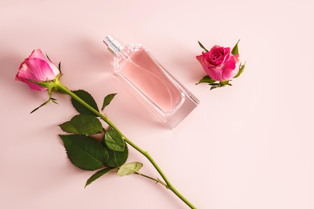 Photo bouteille élégante de parfum ou de spray cosmétique pour femmes sur fond rose avec une délicate coupe de thé, une rose et un bourgeon de rose vue supérieure concept de beauté et de parfumerie