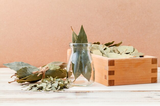 Bouteille de feuilles de laurier séchées avec mise au point sélective sur fond en bois.