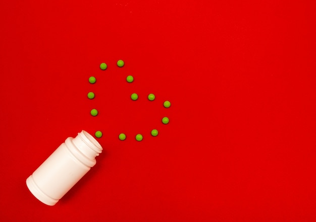 Sur une bouteille de fond rouge et coeur fait de pilules vertes. Concept de la Saint-Valentin.