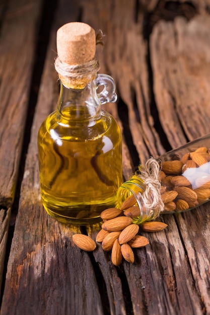 Bouteille d&#39;huile d&#39;amande et d&#39;amandes sur le vieux fond de table en bois