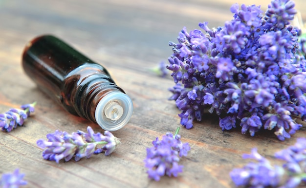 Bouteille d'huile essentielle et bouquet de fleur de lavande sur une table en bois