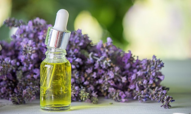 Photo une bouteille d'huile essentielle avec des brindilles de lavande en fleurs fraîches