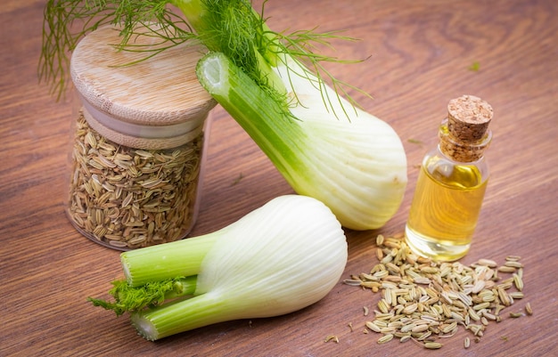 Photo une bouteille d'huile essentielle de fenouil avec des brindilles de fenouil vert frais et des graines de fenouil en arrière-plan