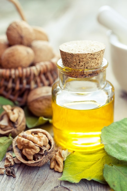 Bouteille d'huile essentielle de noix et panier avec noix sur la vieille table de cuisine