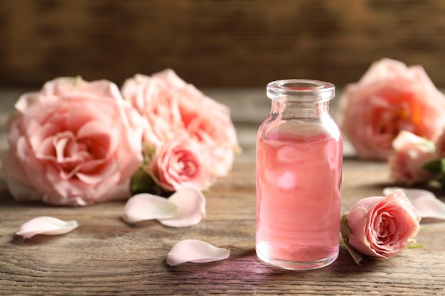 Bouteille d'huile essentielle de rose et de fleurs sur un espace de table en bois pour le texte