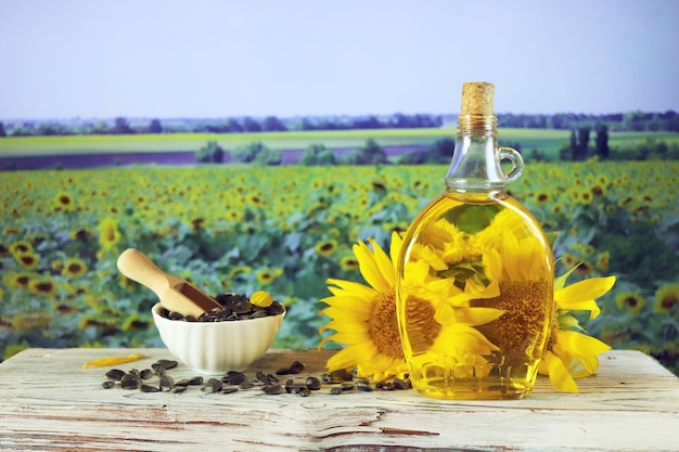 Une bouteille d'huile, des fleurs et des graines de tournesol fraîches sur la table, des produits biologiques, de la récolte