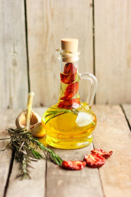 Bouteille d'huile d'olive avec tomates séchées, romarin, ail