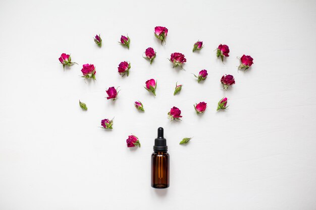 Une bouteille d&#39;huile de rose et de fleurs dans un plat poser