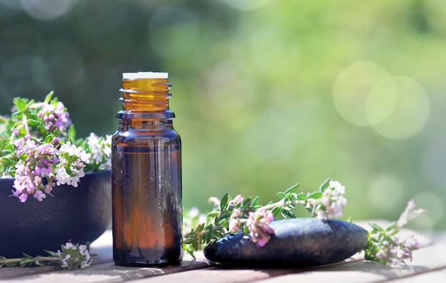 Bouteille d'huiles essentielles renversées sur une table avec des fleurs de lavande sur fond vert bokeh