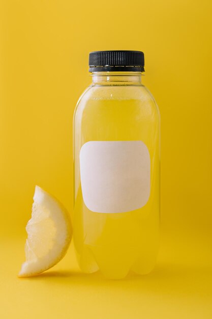 Bouteille de jus de citron frais sur fond jaune