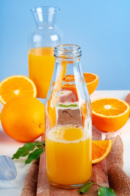 Bouteille de jus d'orange et oranges fraîches sur table