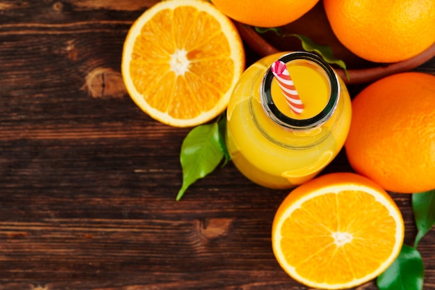 Bouteille de jus d'orange avec des oranges sur une table en bois