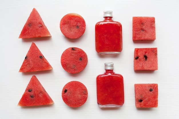 Bouteille de jus de pastèque fraîche avec des morceaux de melon d&#39;eau sur blanc