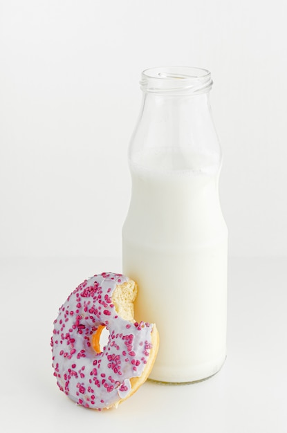 Bouteille de lait et beignet saveur de fruits avec morsure sur fond blanc